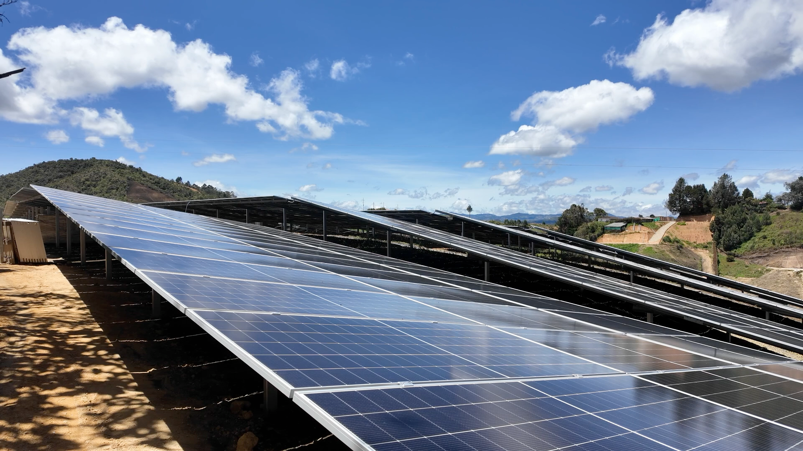 Vista aérea con dron de un extenso parque de paneles solares instalado sobre una colina rodeada de bosque, escena del video corporativo de Solenica